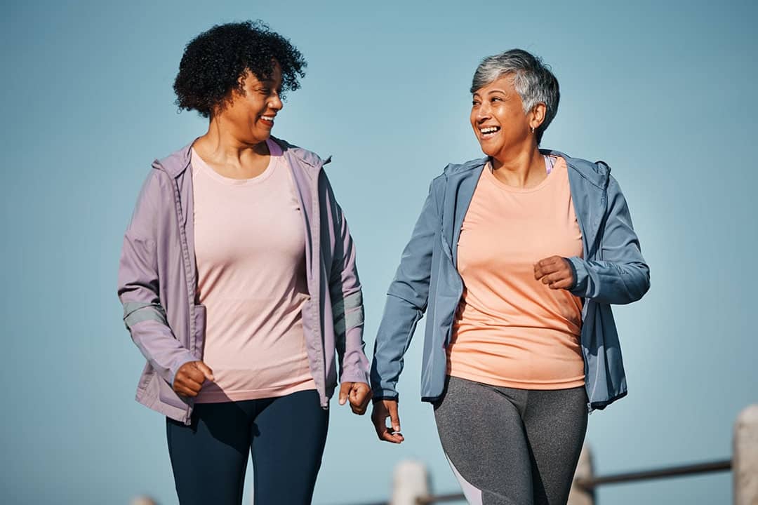 Two senior women talking a walk together outdoors.